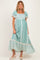 woman wearing a teal floral print maternity dress with short ruffled sleeves and a tiered hem, showing her baby bump