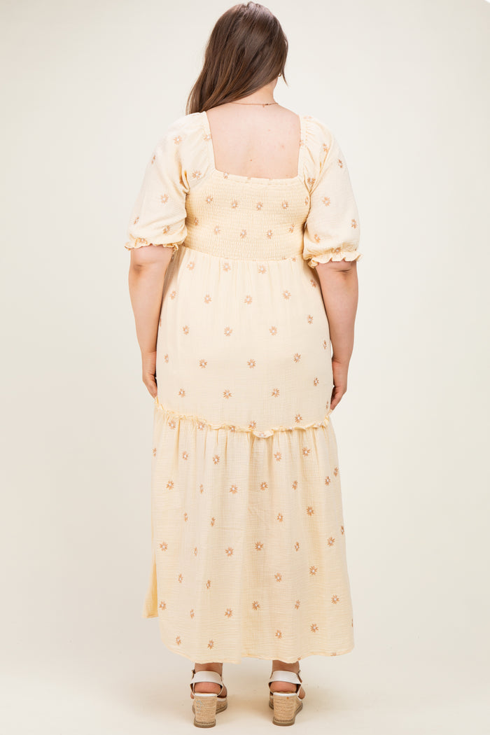 woman wearing a yellow floral maternity plus maxi dress with puff sleeves and a tiered skirt, showcasing a baby bump