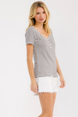 woman wearing a white and black striped short sleeve top with a scoop neckline and white distressed shorts