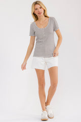 woman wearing a striped black and white short sleeve t-shirt and white frayed hem shorts with white sneakers