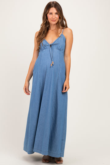 woman wearing a blue denim maternity maxi dress with a tie front and spaghetti straps, showcasing her baby bump