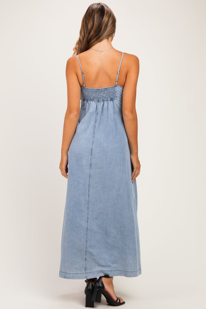 woman wearing a light wash denim maternity maxi dress with a smocked back and thin straps