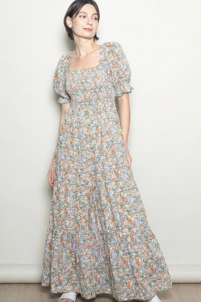 woman wearing a floral print maxi dress with square neckline and puff sleeves, standing against a light background