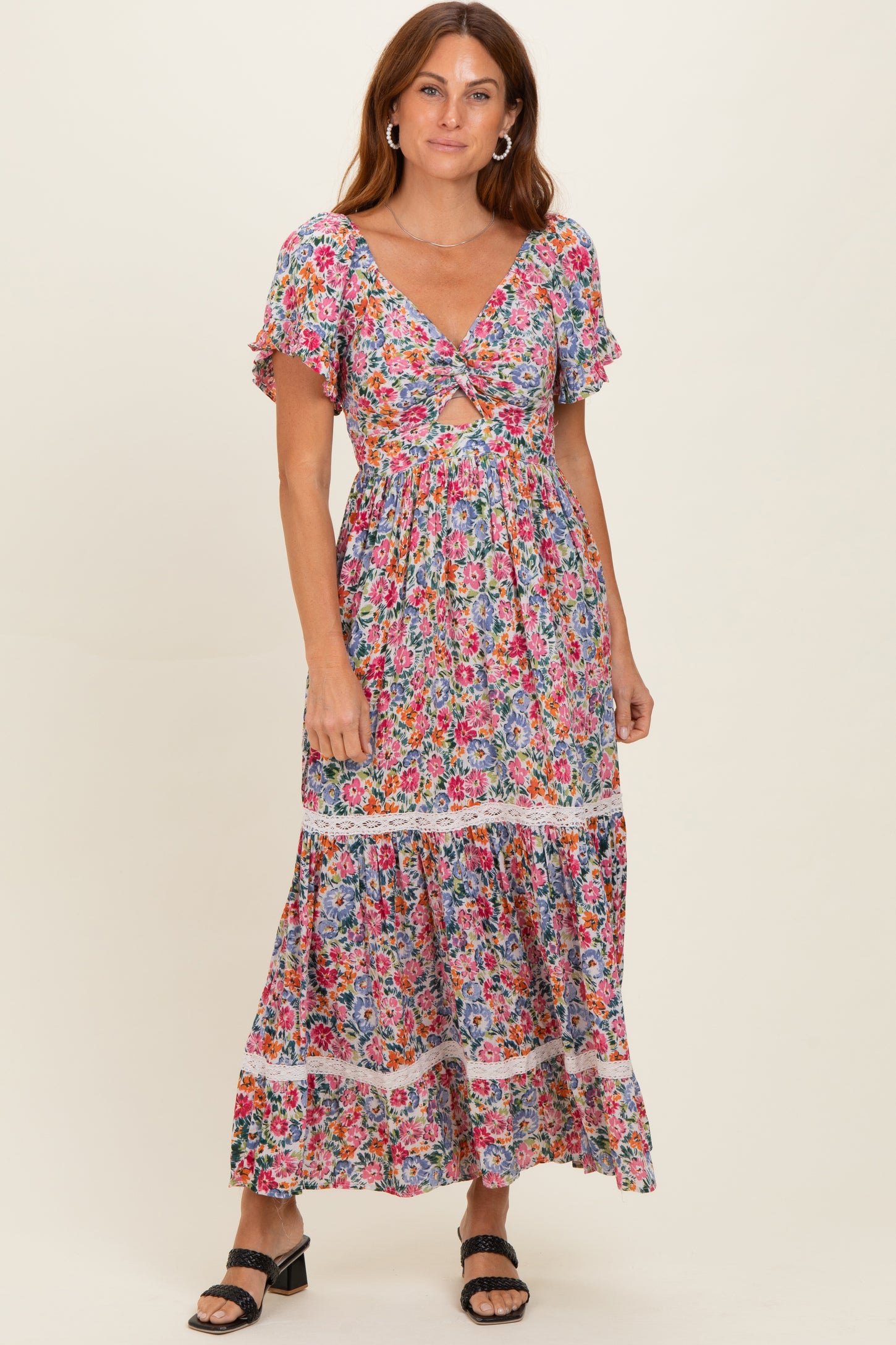 woman wearing a colorful floral maxi dress with short flutter sleeves and a tiered skirt