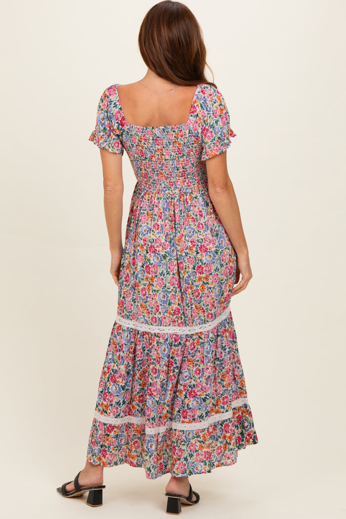 woman wearing a colorful floral maxi dress with short puff sleeves and a tiered skirt, shown from the back