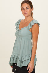 woman wearing a light green maternity top with ruffled sleeves and a flared hemline