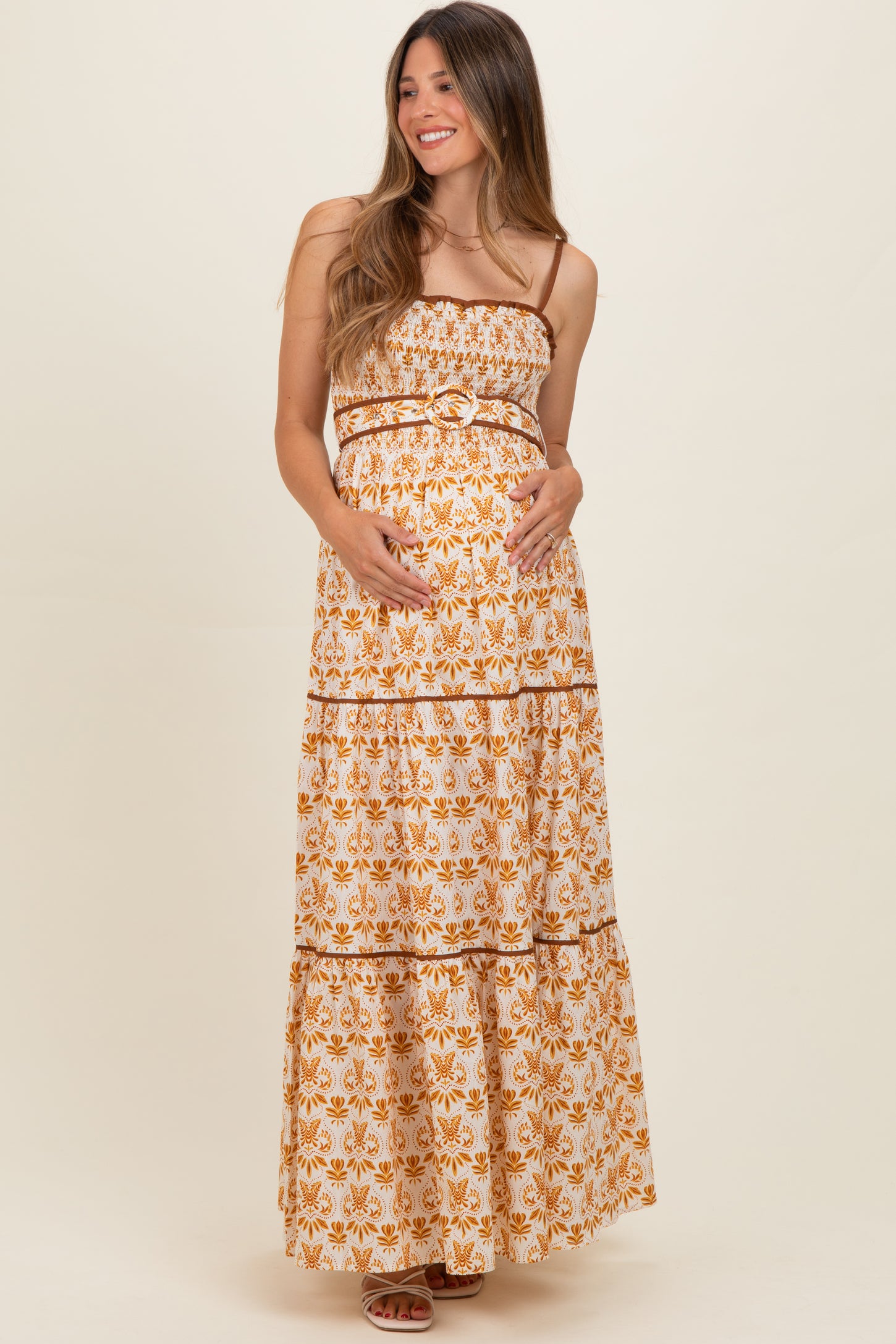 woman wearing a floral print strapless maternity maxi dress and holding her baby bump