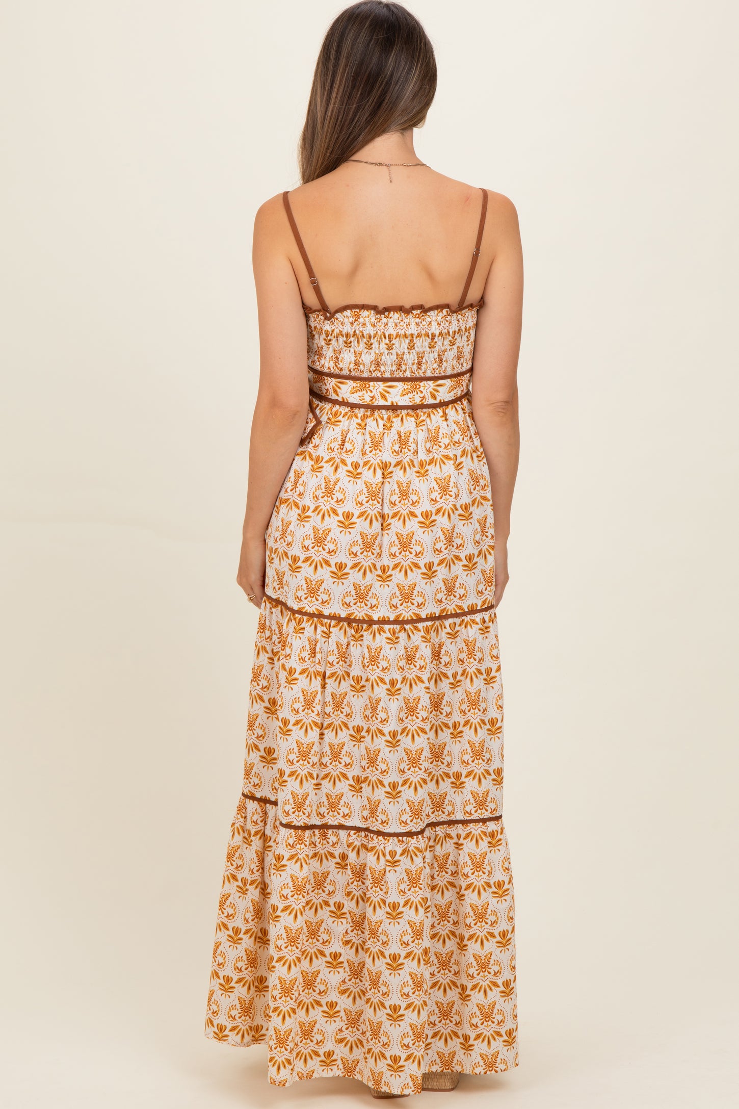 woman wearing a floral print maternity maxi dress with spaghetti straps and a tiered design, showing a baby bump