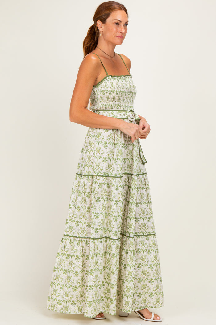 woman wearing a green and white floral maxi dress with spaghetti straps and a fitted bodice, standing in profile