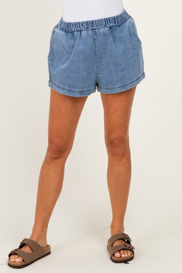 woman wearing light blue denim shorts with an elastic waistband and side pockets, styled casually with brown sandals