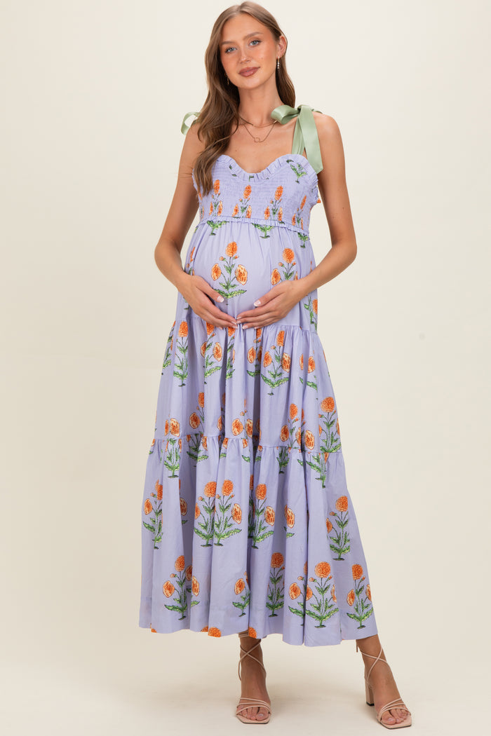 woman wearing a lavender floral maternity maxi dress with tie straps and holding her baby bump