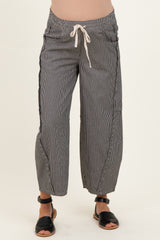 woman wearing black and white striped maternity pants with a drawstring waist and cropped length, showcasing her baby bump