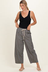 woman wearing a black sleeveless top and black and white striped wide-leg pants with a drawstring waist