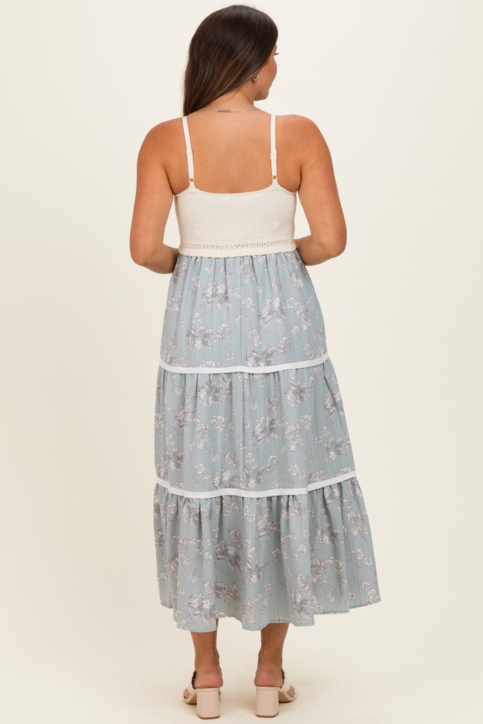 woman wearing a light blue floral maternity maxi dress with tiered design and a smocked bodice