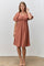 woman wearing a rust-colored puff sleeve dress with a square neckline and gathered detailing