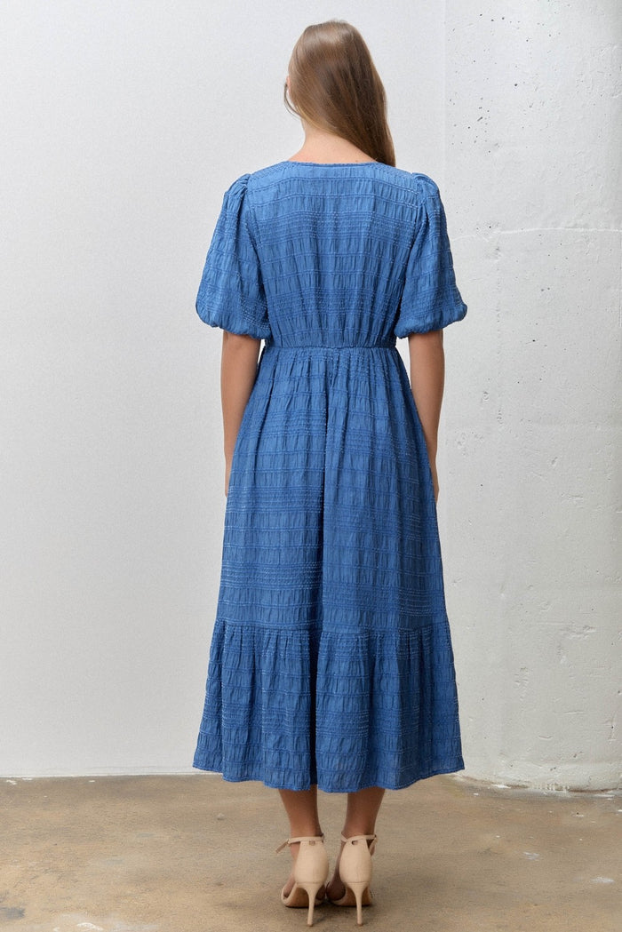 woman wearing a blue puff sleeve midi dress with a tiered skirt, viewed from the back