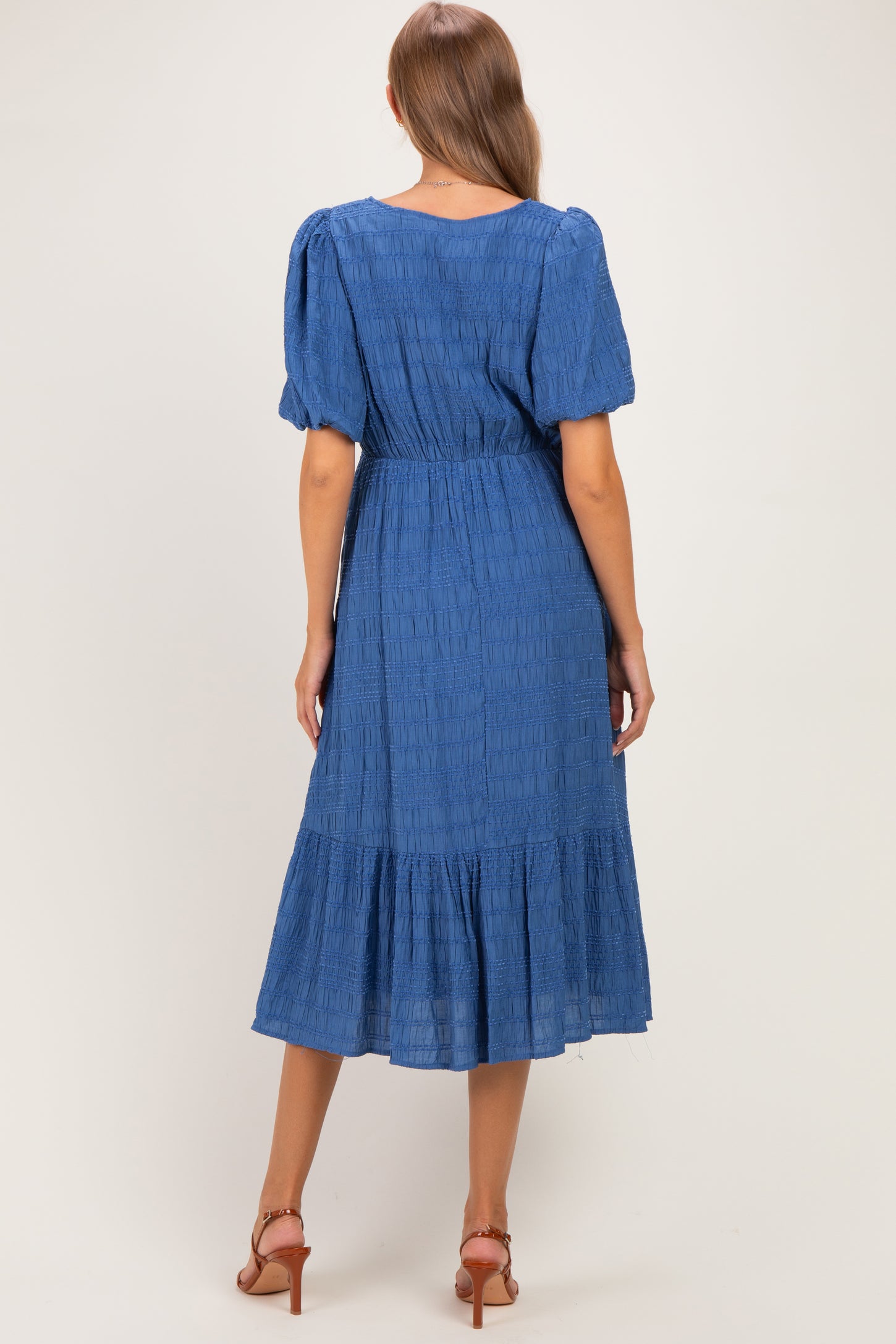 woman wearing a blue maternity dress with short puff sleeves and a tiered skirt, showcasing a comfortable fit