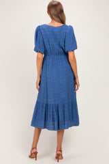 woman wearing a blue maternity dress with short puff sleeves and a tiered skirt, showcasing a comfortable fit