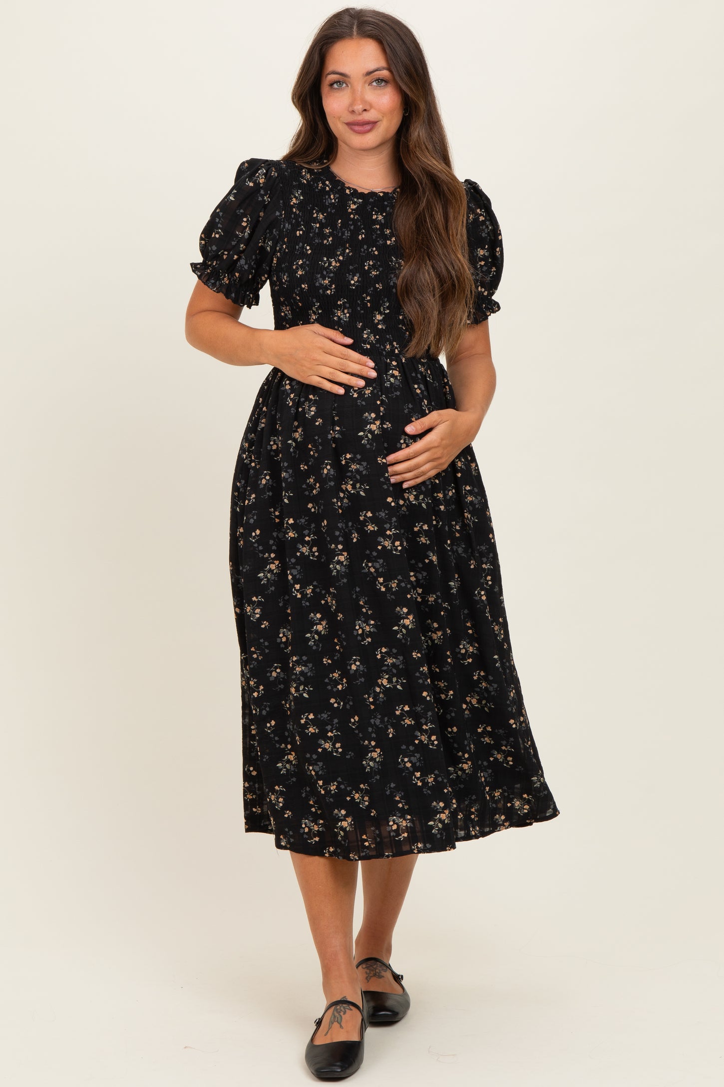 woman wearing a black floral maternity dress with puff sleeves and a baby bump visible