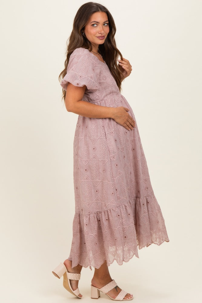 woman wearing a pink lace maternity dress with short flutter sleeves and holding her baby bump