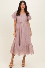 woman wearing a light mauve puff sleeve midi dress with a tiered ruffle hem and eyelet lace detailing