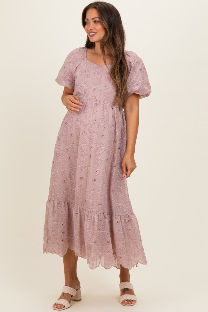 woman wearing a dusty pink embroidered maternity dress with puff sleeves and a ruffle hem, showcasing her baby bump