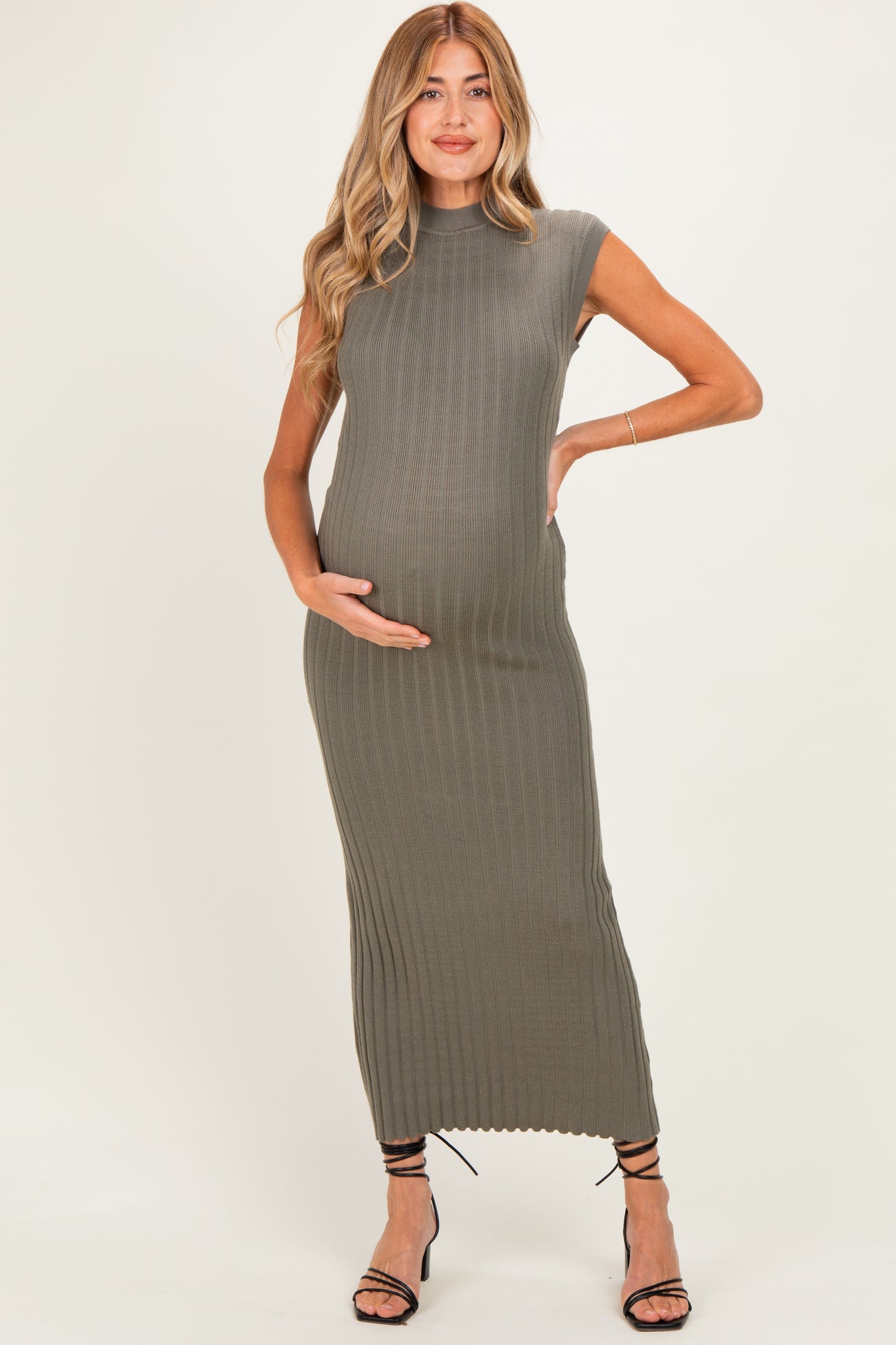 woman wearing a fitted olive green maternity dress with ribbed detailing and holding her baby bump