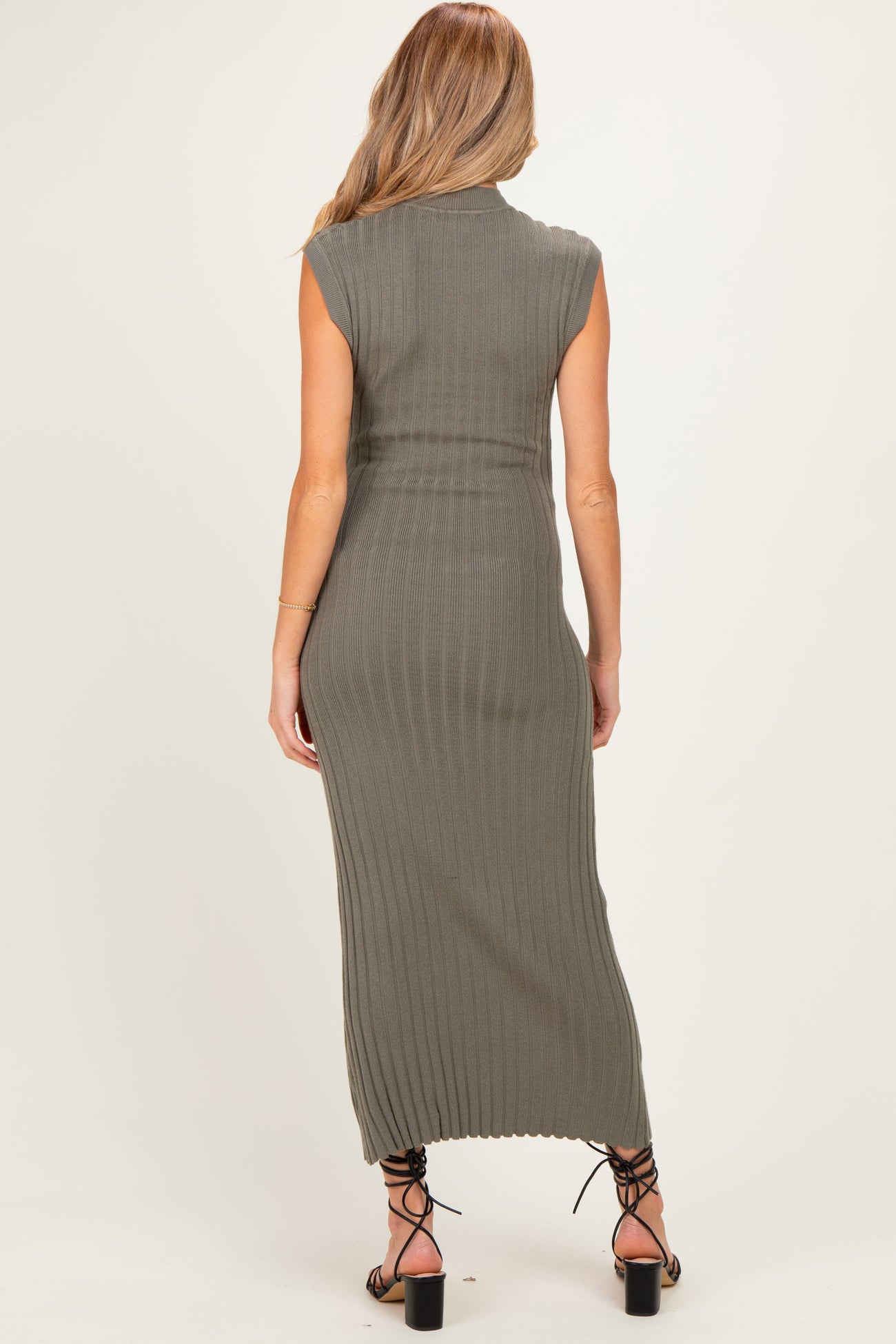 woman wearing a fitted olive green ribbed maxi dress with short sleeves, showing a side view of the back and slits