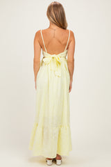 woman wearing a yellow eyelet maxi dress with a back tie detail and ruffled hem
