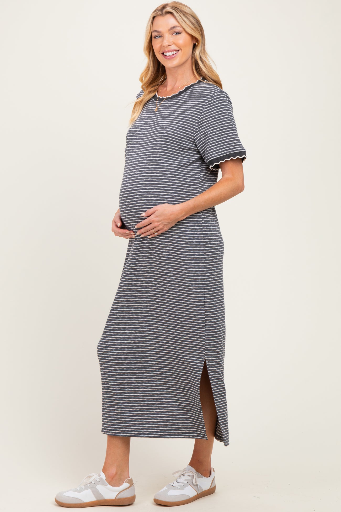 woman wearing a navy and white striped maternity dress with short sleeves and side slits, showing her baby bump