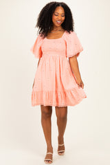 woman wearing a coral puff sleeve mini dress with embroidered flowers and a ruffled hem