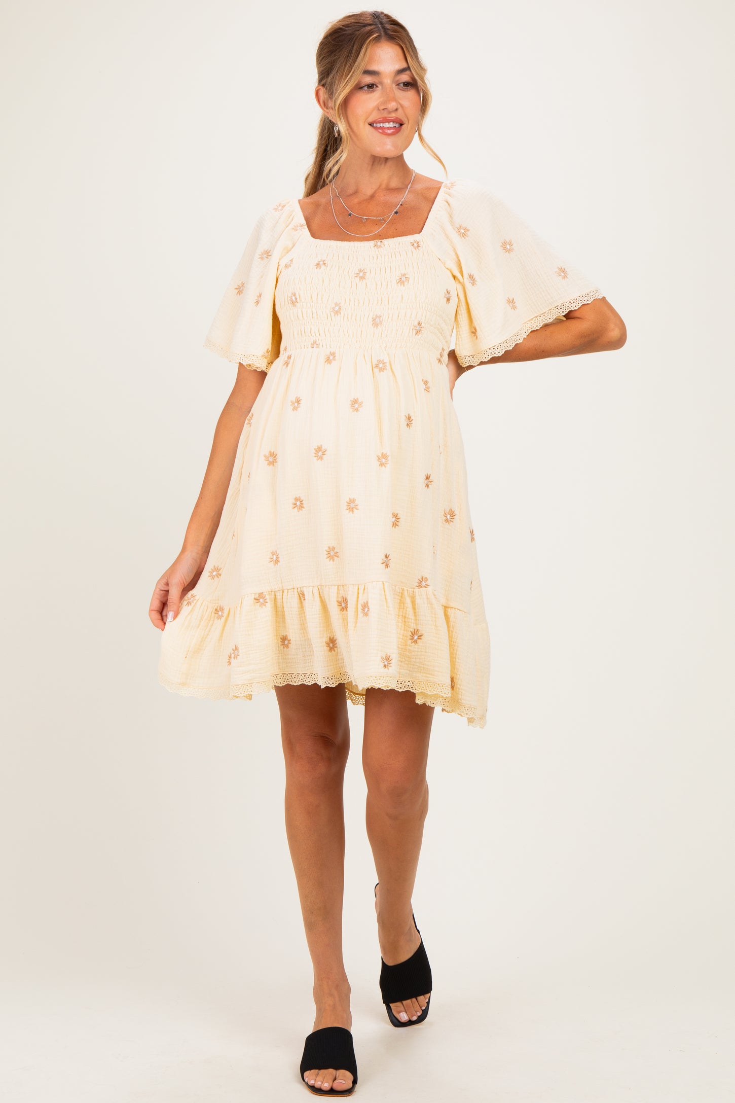 woman wearing a yellow floral maternity dress with puff sleeves and a tiered skirt