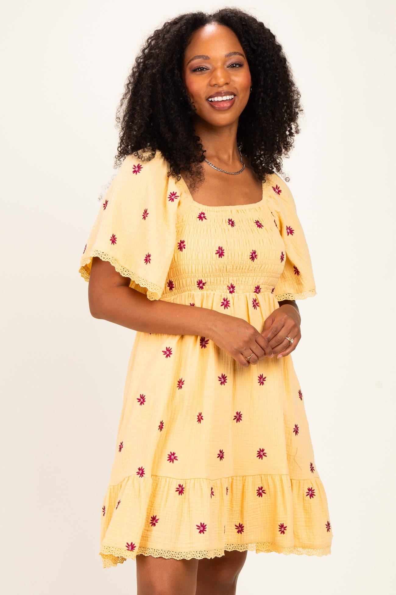 woman wearing a yellow floral smocked dress with short sleeves and a tiered hem