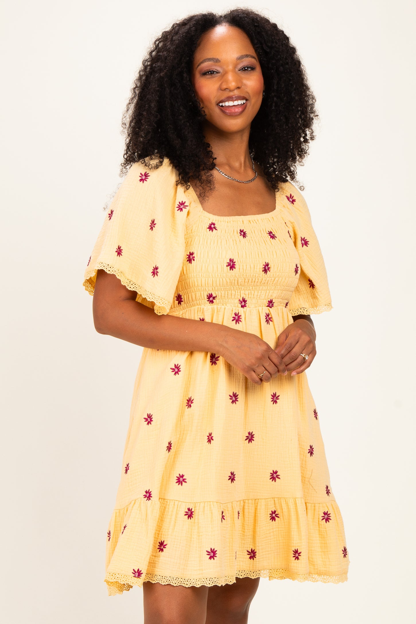woman wearing a yellow floral smocked dress with short sleeves and a tiered hem