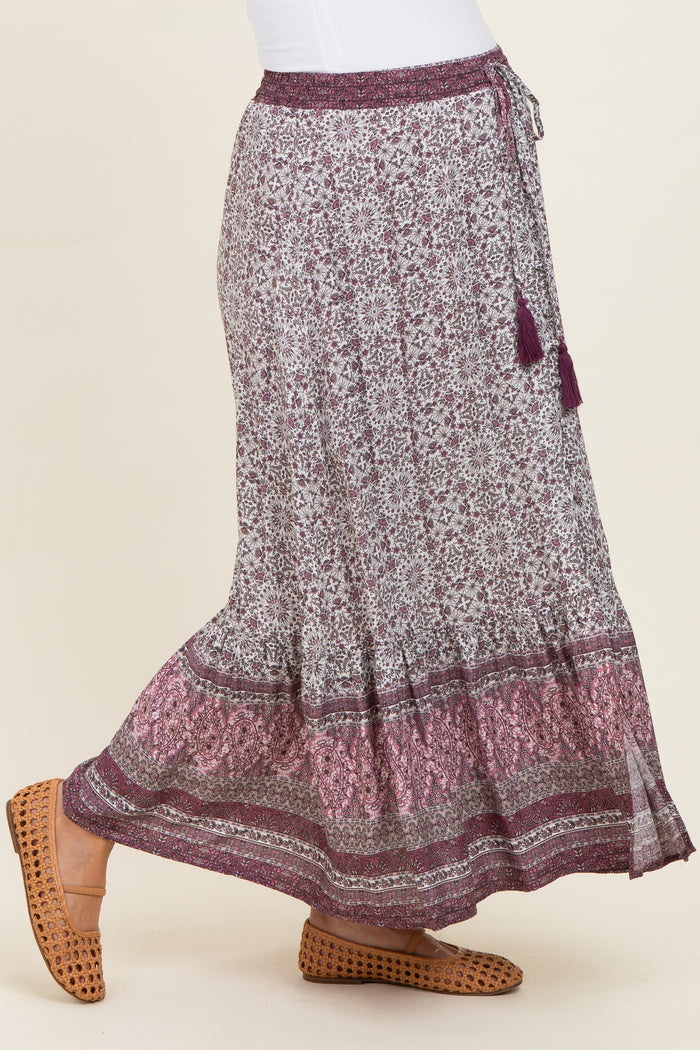woman wearing a purple floral maternity maxi skirt with tassel detailing and a stretchy waistband
