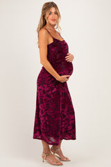 woman wearing a burgundy floral maternity dress with adjustable straps and holding her baby bump