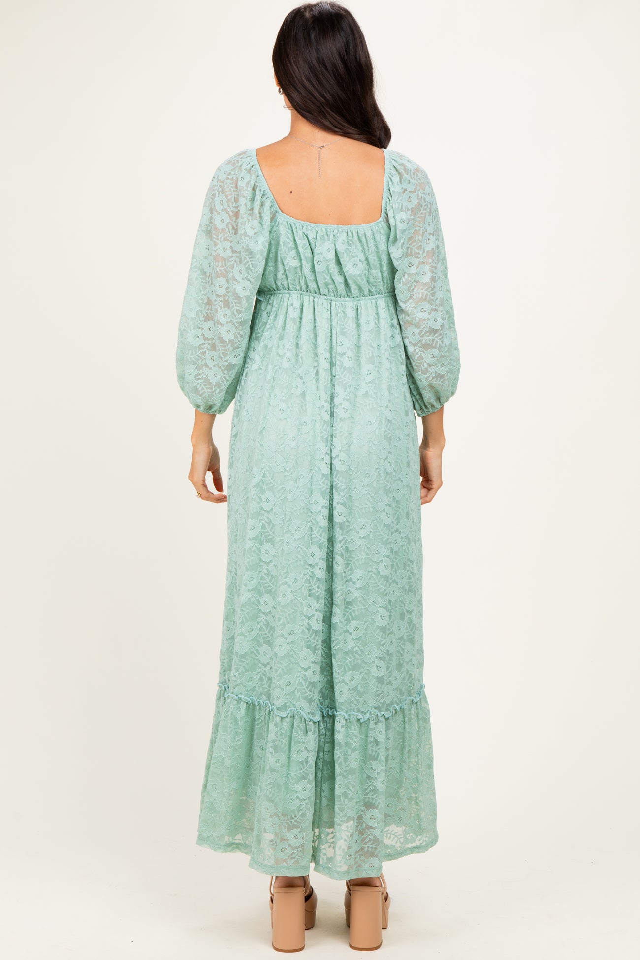 woman wearing a mint green lace maxi dress with balloon sleeves and a ruffled hem, viewed from the back