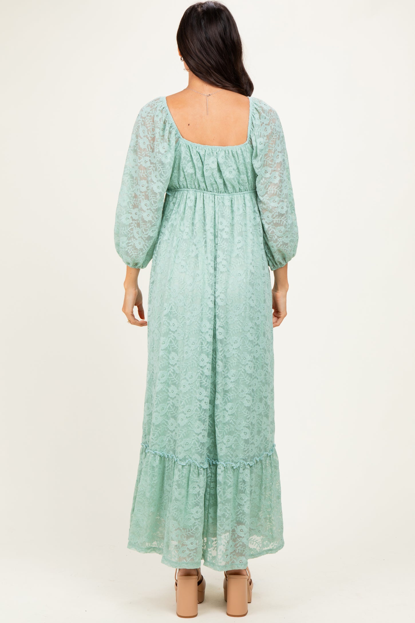 woman wearing a mint green lace maxi dress with balloon sleeves and a ruffled hem, viewed from the back