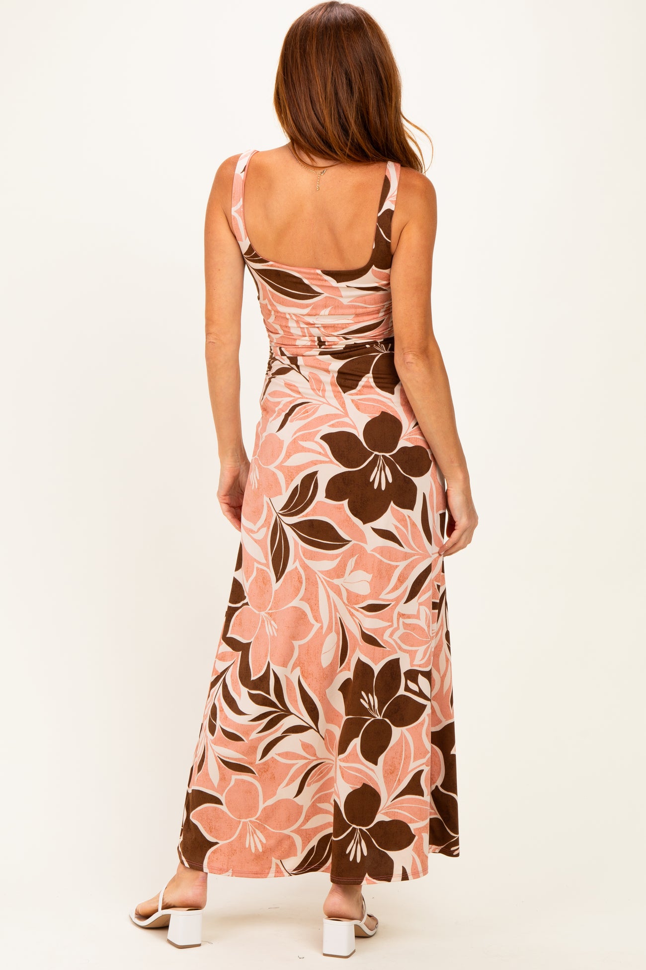 woman wearing a pink and brown floral maxi dress with a fitted bodice and a flowing skirt, seen from the back