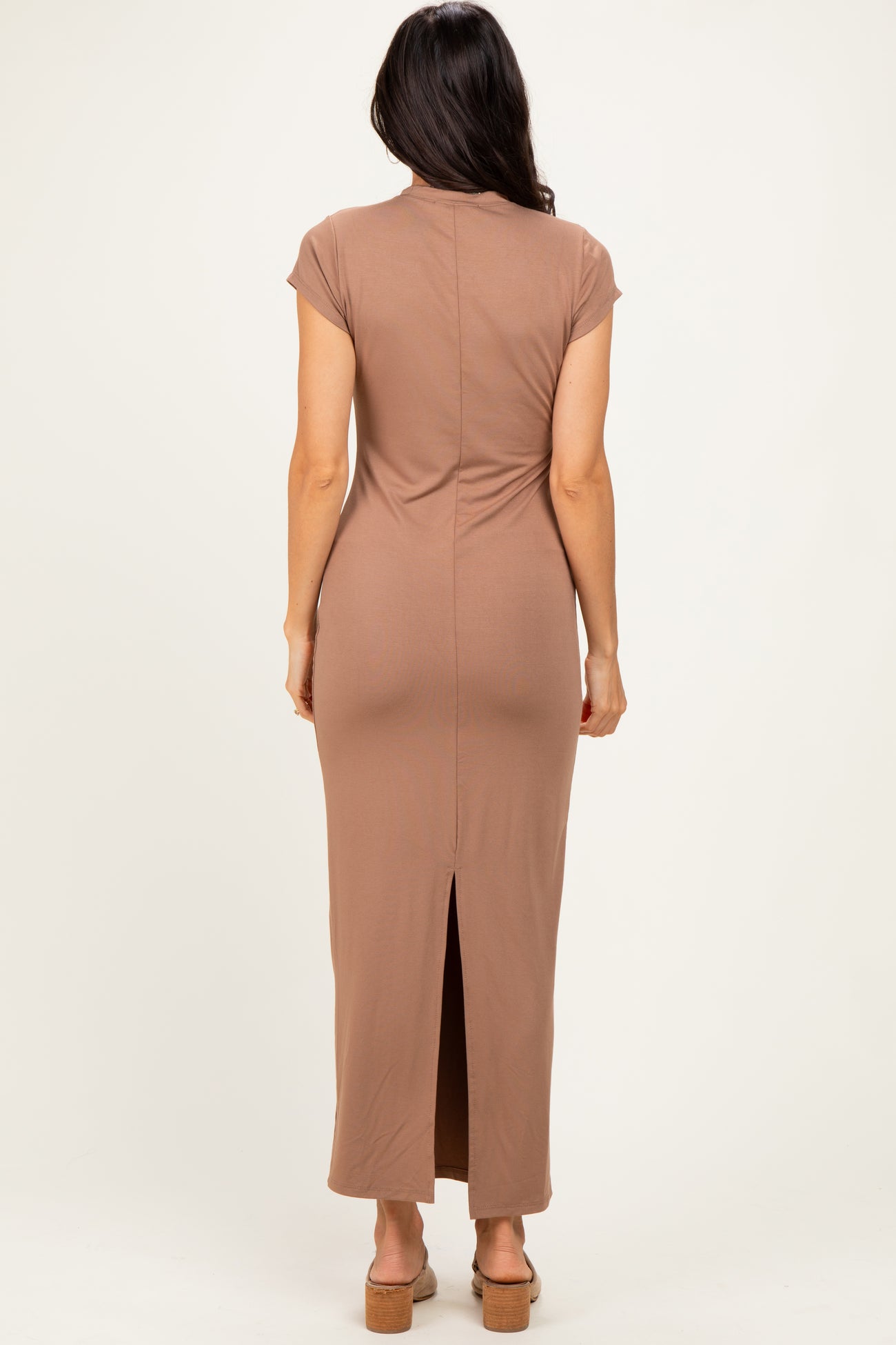 woman wearing a brown short sleeve maxi dress with a back slit and a form-fitting silhouette