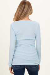 woman wearing a light blue long sleeve maternity top, showing ruching detail at the back