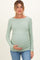 woman wearing a light green long sleeve maternity top and holding her baby bump