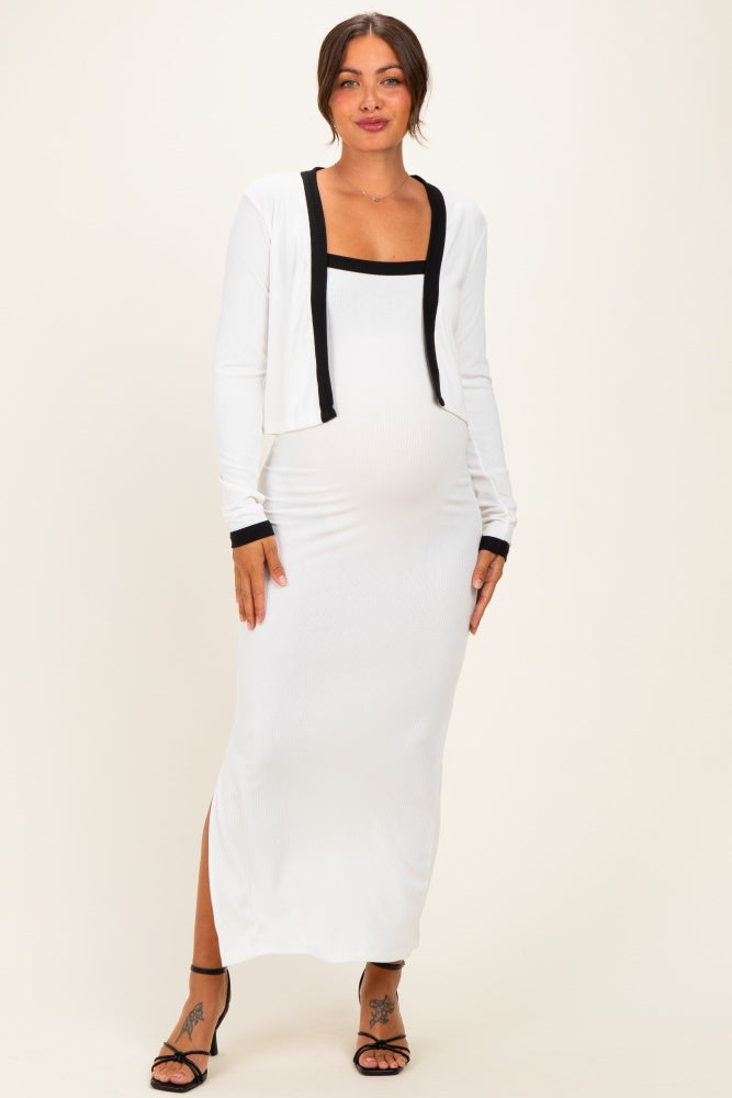 woman wearing a white maternity maxi dress with a black trim cardigan and showing her baby bump