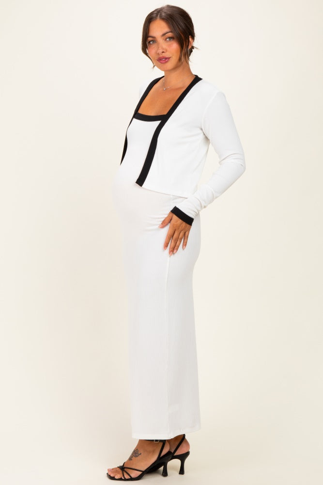 woman wearing a white ribbed maternity dress with black accents, showcasing her baby bump