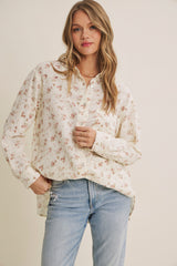 woman wearing a cream floral button-up shirt with long sleeves and relaxed fit, paired with light blue jeans