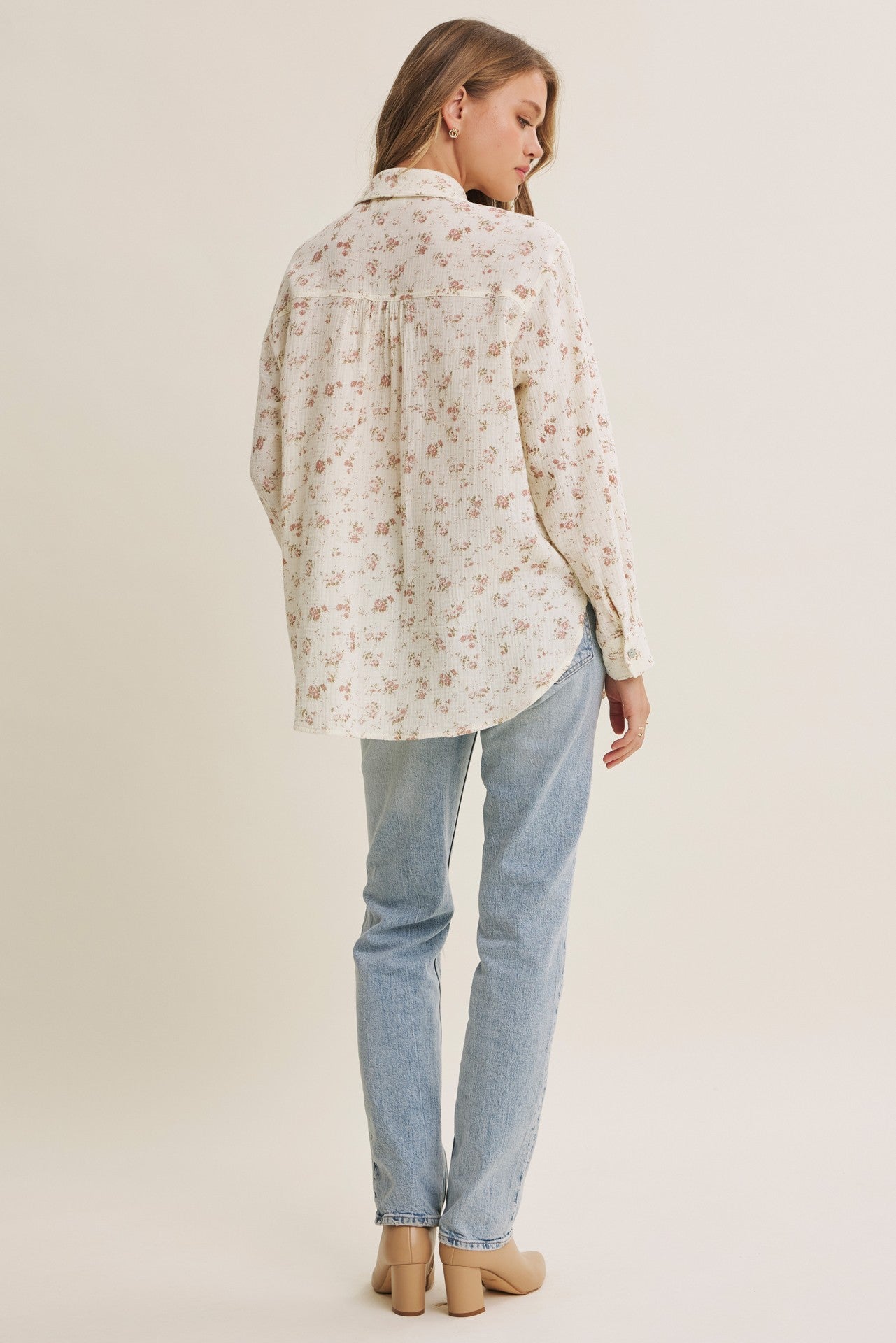 woman wearing a cream floral long sleeve button-up shirt with a relaxed fit and light blue jeans