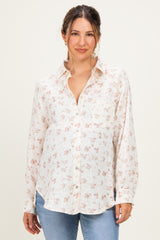 woman wearing a cream floral maternity button-up shirt with a visible baby bump and casual jeans