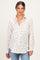 woman wearing a cream floral maternity button-up shirt with a visible baby bump and casual jeans