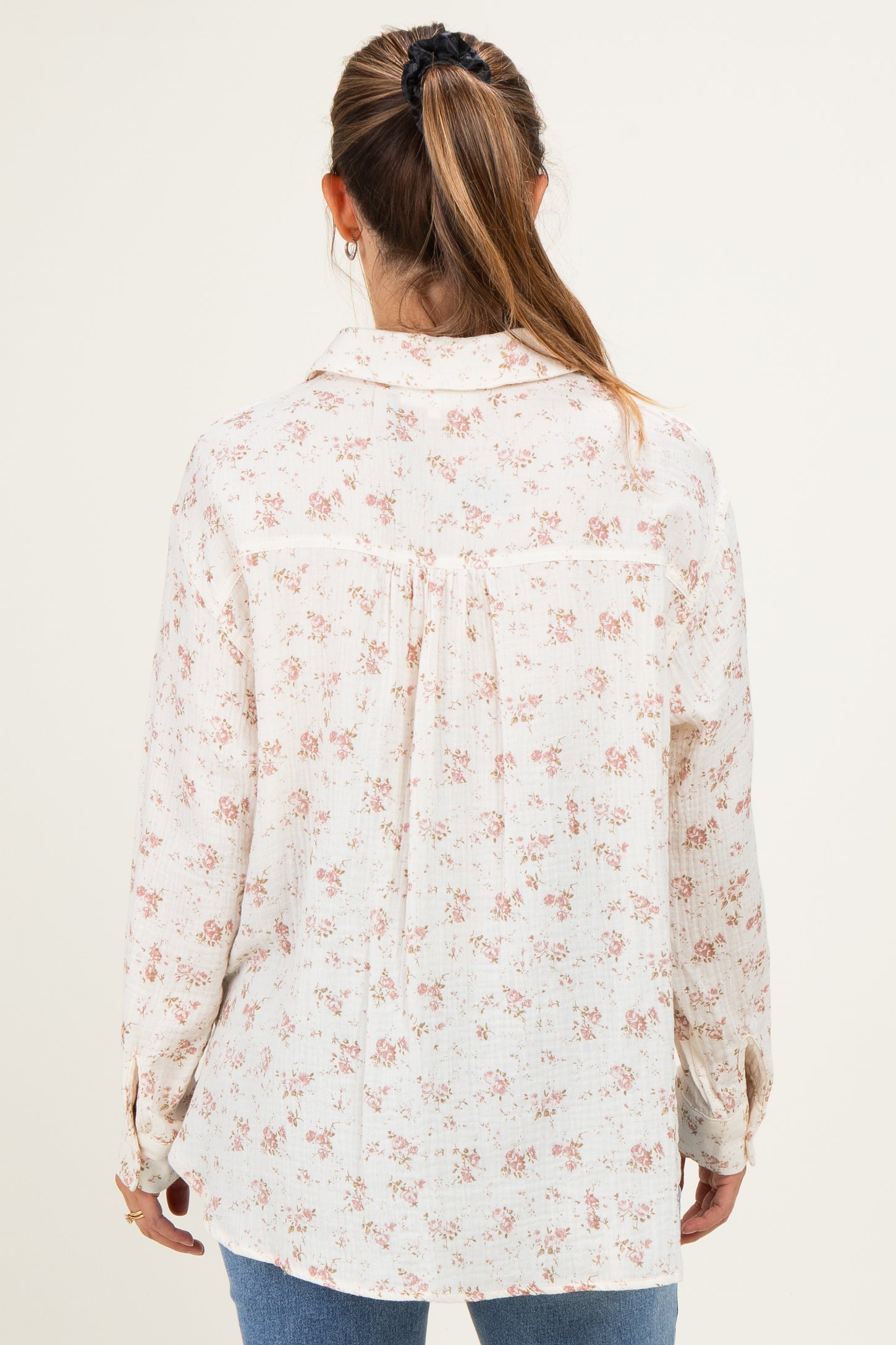 woman wearing a white floral maternity top with long sleeves, shown from the back