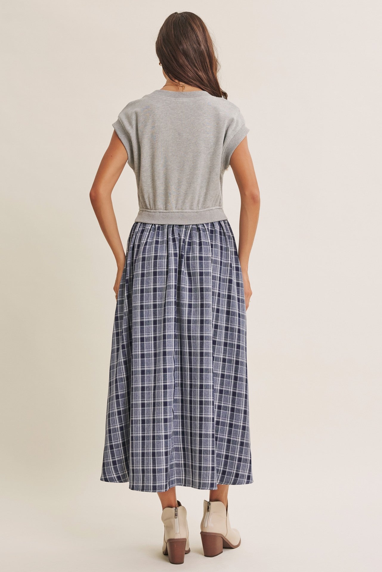 woman wearing a gray short sleeve top and a long navy plaid skirt from the back